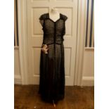 A black lace 1930 evening dress with a floral corsage on the waist band, cut on the bias (the metal