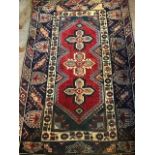 A traditional wool rug, geometric design in red, blue, pink and cream, approximately 120cm by 180cm