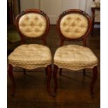 A Pair of Victorian walnut cameo back chairs with leaf carved and pierced frames, buttoned backs and