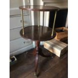 A George III mahogany two tier dumbwaiter, circa 1820, supported on three brass pillars above a