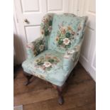 A Georgian style wing back armchair, raised on cabriole legs to front