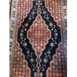 A traditional wool rug, geometric design in blue red and cream, approximately 122cm by 192cm