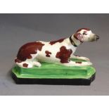 A Staffordshire model of a setter laying on an oblong base, circa 1820, 17.5cm wide and 9cm high