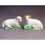 A pair of Yorkshire Pottery models of a ewe and a ram, recumbent on green bases, circa 1800, ewe
