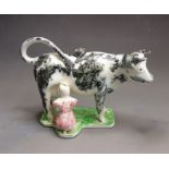 A pottery cow creamer with a milkmaid, probably Yorkshire, circa 1815, 22cm wide, 14cm high