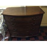 A George III mahogany bow front chest of four long graduated drawers with brass handles on carved