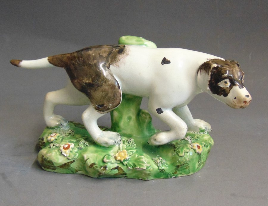 A Staffordshire pearlware model of a pointer, standing on a grassy base, circa 1820, 16cm wide,  9cm