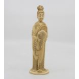 A Japanese walrus ivory figure of a maiden, circa 1920, standing full length enrobed, holding a fan,