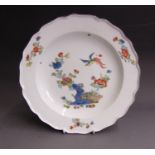 A Meissen deep plate with a scalloped rim line, painted with a bird in flight  over flowers and