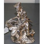 A silver plated figurine, fashioned a seated man with rabbits feeding upon carrots in his hand,