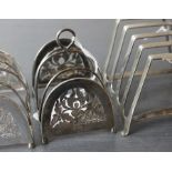 A pair of white metal four division toast racks, of arched form with foliate pierced sides,
