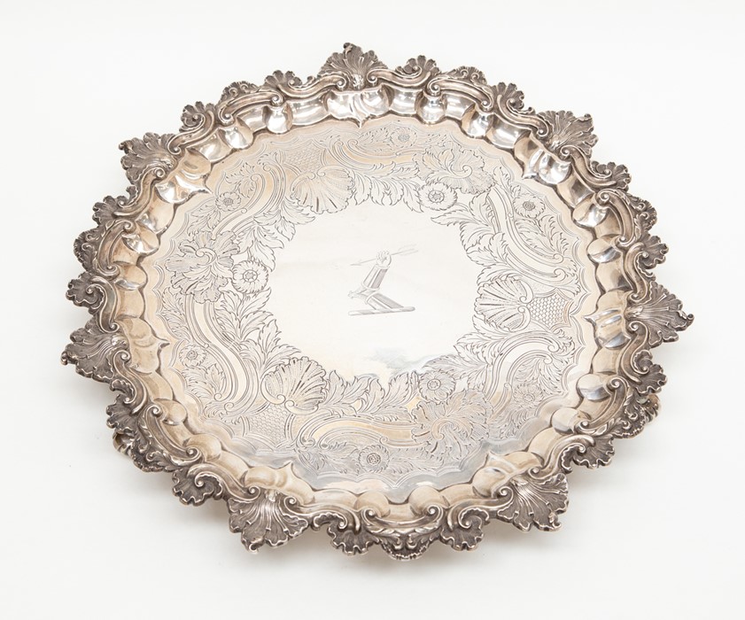 A George IV silver salver with scallop and scroll edge, engraved, raised on heavy scroll feet,