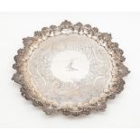 A George IV silver salver with scallop and scroll edge, engraved, raised on heavy scroll feet,