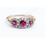 An 18ct gold ruby and diamond ring, comprising three round cut ruby's within diamond set borders,
