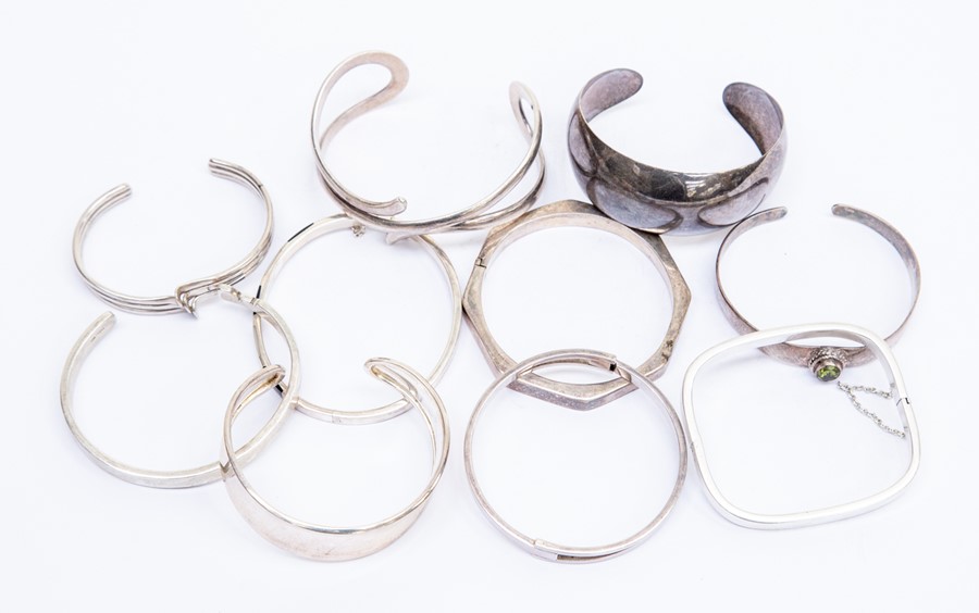 A collection of ten silver bangles, various design s including torque and hinged versions, one