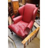 A 20th Century Red Leather wingback armchair on mahogany cabriole support with carved claw feet