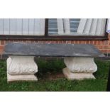 **AWAY** An early 20th century carved stone bench, dark tile top above carved stone plinths.