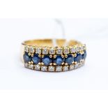 An 18ct sapphire and diamond half hoop ring, comprising a central row of round cut sapphires with