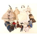 A group of small dolls, some with porcelain heads and others are wooden examples