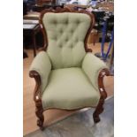 A Victorian walnut armchair, button backed upholstered in green fabric, raised on scrolled feet with