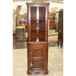 An oak standing corner unit with open shelves to top and cupboard to base.