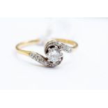 An 18ct gold and diamond cross-over ring, the central stone approx 0.25ct, cross over shoulder set