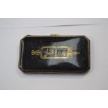 **AWAY** An early 20th Century white metal and black enamelled cigarette case, with gilt decoration