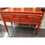A red lacquered 19th century lowboy in the oriental style, with three small drawers.