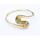 An emerald and diamond bangle,  swirl shaped  design set with  set with emerald cuts and round cut