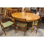 A mid century Walnut veneered extending oval dining table and five dining chairs, including one