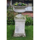 A late 20th century cast stone urn in circular form with egg and dart rim on tapered support to