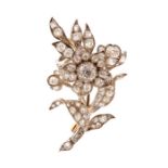 A stylised diamond set spray brooch, the central flower head cluster surrounded by scroll and leaf