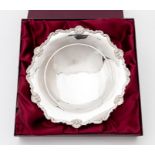 A George V silver shaped circular plain bowl, the border with rocaille and scroll decoration, on