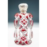 A late 19th Century red flash cut oblong perfume bottle, the silver cover chased with foliage -