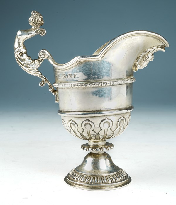 A George II style helmet shaped silver cream jug, shaped border above beaded mid rib, lower