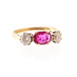 A ruby and diamond three stone 18ct gold ring, the centrally claw set oval cut ruby weighing