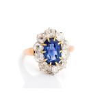 A sapphire and diamond oval cluster ring, the central rectangular cushion cut accompanied by a G.C.S