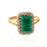 An emerald and diamond  rectangular cluster ring, the central rectangular step cut emerald