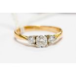 An 18ct gold and diamond three stone ring, with central cushion cut brilliant of 0.56ct flanked by