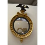 A 19th Century gilt painted circular mirror, carved ebonised design finial on a platform above a