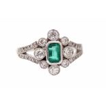 An emerald and diamond 18ct gold ring, the central set emerald approx 0.75ct, with a floral surround