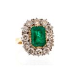 A 2 carat emerald and diamond cushion shaped cluster ring, the central step-cut emerald approx 9.2mm
