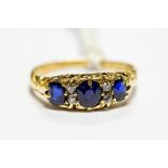 An 18ct gold ring, set with three blue sapphires with diamond set accents, size R, total gross