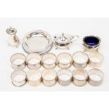 A collection of silver items to include a mustard, pepper and salt set, various napkin rings and a