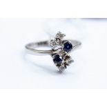A sapphire and diamond ring, cross over shoulders with round cut sapphire and brilliant cut