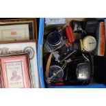 A collection of travel clocks, camera items, bible and commemorative framed pictures