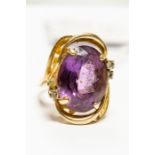 A large amethyst and diamond dress ring, claw set oval cut amethyst with four small diamond accents,