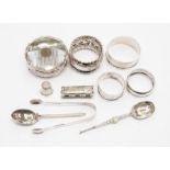 Four silver napkin rings; an aesthetic silver brooch; sugar nips; two silver spoons; silver thimble,