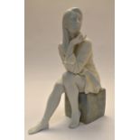 A Lladro study of a young lady seated on a marble style block.