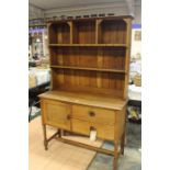 An Arts & Crafts style oak dresser and rack base with two drawers and single door raised on turned